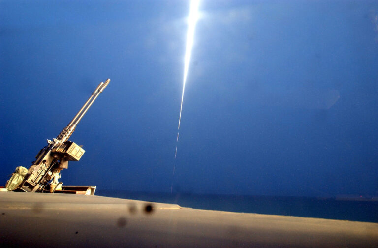 The trace of a Tomahawk missile launched from the deck of the USS John McCain DDG 56 destroyer shines past a twin 50 mm machine gun, in the northern Gulf waters Saturday, March 22, 2003. The United States continued its aerial assault on military targets in Baghdad and other cities Saturday, while invading troops were advancing into southern Iraq. (AP Photo/Adam Butler)