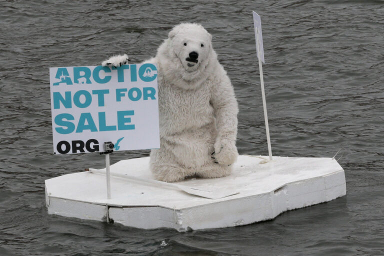 A greenpeace activist dressed as a polar bear sits on the wooden block of ice on the Moskva River protesting against plans of oil companies' drilling in the Arctic, in Moscow, Russia, Monday, April 1, 2013. (AP Photo/Mikhail Metzel)