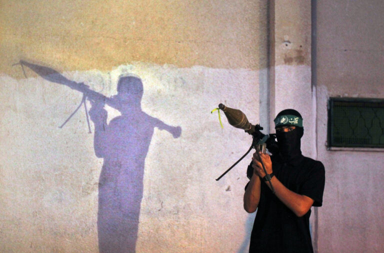 A Palestinian masked member of the 'Ezz Al-Din Al Qassam' militia, the military wing of Hamas, holds his weapon during a march along the streets of Gaza City, Wednesday, Sept. 4, 2013. Arabic read on a headband 