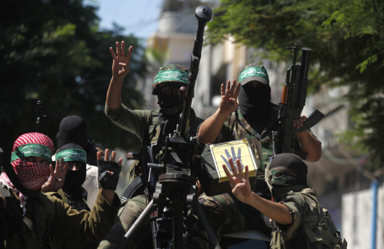 Palestinian members of the Ezz Al-Din Al Qassam militia, the military wing of Hamas, hold up four fingers, a sign that protesters say symbolizes the Rabaah al-Adawiya mosque in Cairo, Egypt, as holding their weapons during a march in Beit Lahia, northern Gaza Strip, Friday, Sept. 6, 2013. (AP Photo/Hatem Moussa)