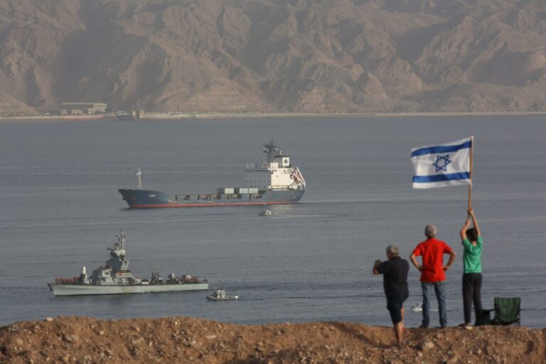 epa04115451 People wave an Israeli flag as the Klos-C cargo vessel (B) accompanied by Israeli Navy ships approaches the port of Eilat in the Red Sea, Israel, 08 March 2014. Israel on 05 March had intercepted a cargo vessel in the Red Sea carrying dozens of advanced rockets. Israel believes the missiles were meant to be delivered to militants in the Gaza Strip, as they said they had been tracking the missiles movements for months. The Syrian-made M-302 rockets have a range of up 160 kilometres with warheads of up to 150 kilogrammes, Israeli officials said. EPA/ABIR SULTAN EPA/ABIR SULTAN