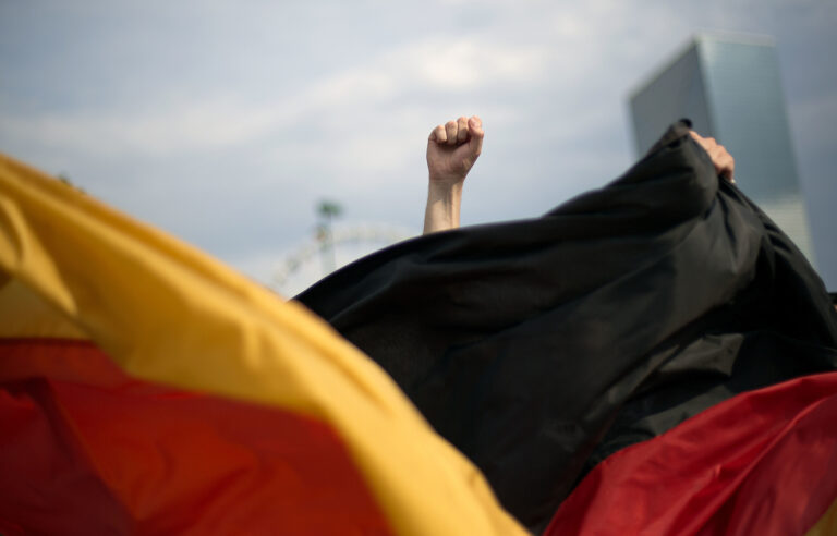 The fist of Lucke Ehret, of Mannheim, Germany, is thrust in the air behind the German flag as he celebrates with fellow fans after Germany defeated Argentina in the 2014 World Cup soccer final match at a viewing party in Centennial Olympic Park, Sunday, July 13, 2014, in Atlanta. (AP Photo/David Goldman)