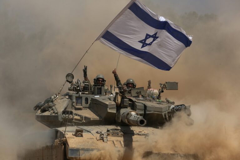 epa04339517 Israeli soldiers wave from their Merkava tank with an Israeli flag as troops pull back from the Gaza Strip, 03 August 2014. Ground troops withdrew from the Gaza Strip as Israel wrapped up an operation to destroy tunnels, but airstrikes continued, killing at least 15 Palestinians. A military official said that most combat troops were back in Israeli territory by the morning. Officials stressed that some soldiers would remain in key positions, especially on the inside of the Gaza-Israel border, between the first lines of houses and the border fence. EPA/ATEF SAFADI
