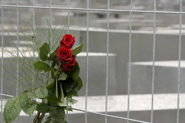 Rote Rosen stecken am Dienstag, 10. Mai 2005, am Bauzaun, der das Holocaust Mahnmal in Berlin einzaeunt. Am Dienstag wird das Mahnmal fuer die ermordeten Juden Europas offiziell eroeffnet. Ab Donnerstag ist es auch fuer Besucher offen. (AP Photo/Franka Bruns) ---Red roses are pinned to the contruction fence that surrounds the national Holocaust Memorial in Berlin, Tuesday, May 10, 2005. After years of debate and delay, Germany on Tuesday finally dedicated its national Holocaust memorial, an undulating field of concrete slabs on a site resonant with both the terror of German history and the vibrancy of today's reunited Berlin. (AP Photo/Franka Bruns)