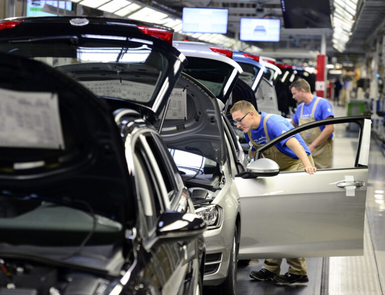 Workers complete cars at the assembly line during the so called 'Open Door Day' to celebrate the 25th anniversary of the plant of the German manufacturer Volkswagen Sachsen in Zwickau, eastern Germany, Sunday, Sept. 6, 2015. More than 4.9 Million vehicles (Golf and Passat) have left the production facilities since foundation on the Zwickau plant in 1990. (AP Photo/Jens Meyer)