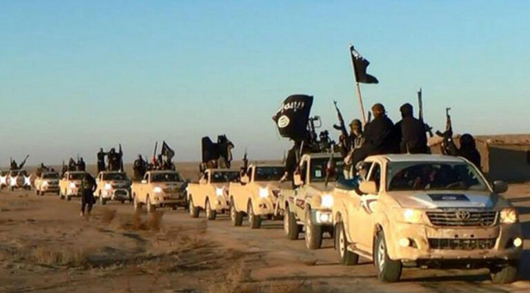 In this undated photo released by a militant website, which has been verified and is consistent with other AP reporting, militants of the Islamic State group hold up their weapons and wave its flags on their vehicles in a convoy on a road leading to Iraq, while riding in Raqqa city in Syria. When world leaders convene for the U.N. General Assembly debate Monday, Sept. 28, 2015, it will be a year since the U.S. president declared the formation of an international coalition to 