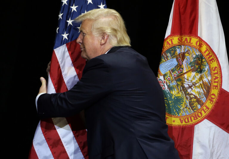 Republican presidential candidate Donald Trump pauses during his campaign speech to hug the American flag Saturday, June 11, 2016, in Tampa, Fla. (KEYSTONE/AP Photo/Chris O'Meara)