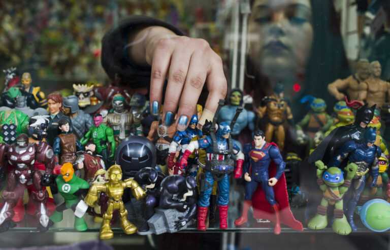 A woman places a toy figure of Captain America amid a collection of super hero and comic action figures on a shelf at a used toys' shop in Santiago, Chile, Friday, June 24, 2016. (AP Photo/Esteban Felix)