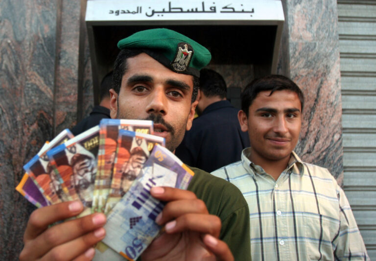 A Palestinian policeman displays money he withdrew for his salary from a bank machine at the Palestine Bank in Gaza City, Sunday, June 4, 2006. Palestinian workers begin drawing partial salaries from cash machines in the Gaza Strip Sunday evening after a three-month delay.The Bank of Palestine announced it was opening its ATM network, and workers began taking out money. The Palestinian government, headed by Hamas, said it would deposit 1,500 shekels ($331, 257), in the accounts of the 40,000 lowest-paid workers. The finance minister said the other 125,000 would have to wait. (KEYSTONE/AP Photo/Khalil Hamra)