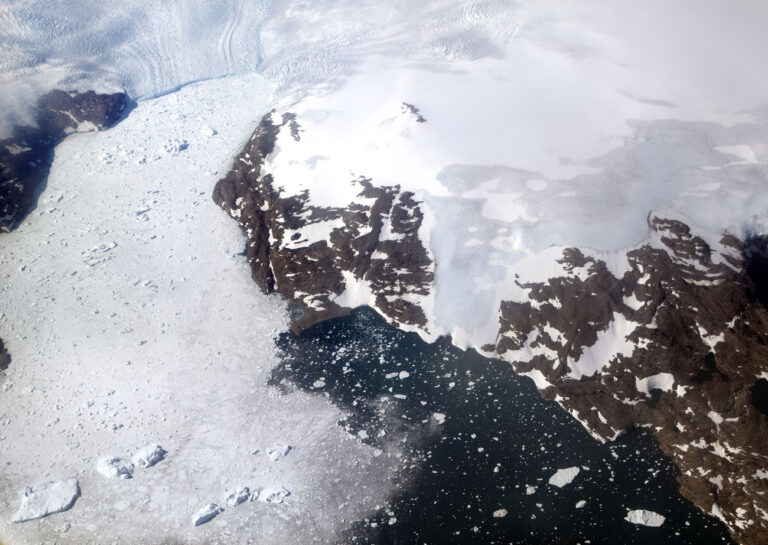 A glacier at left calves icebergs into a fjord off the Greenland ice sheet in southeastern Greenland, Thursday, Aug. 3, 2017. The Greenland ice sheet, the second largest body of ice in the world which covers roughly 80 percent of the country, has been melting and its glaciers retreating at an accelerated pace in recent years due to warmer temperatures. If all of that ice melts, sea levels will rise by several meters, though there will be regional differences. (AP Photo/David Goldman)