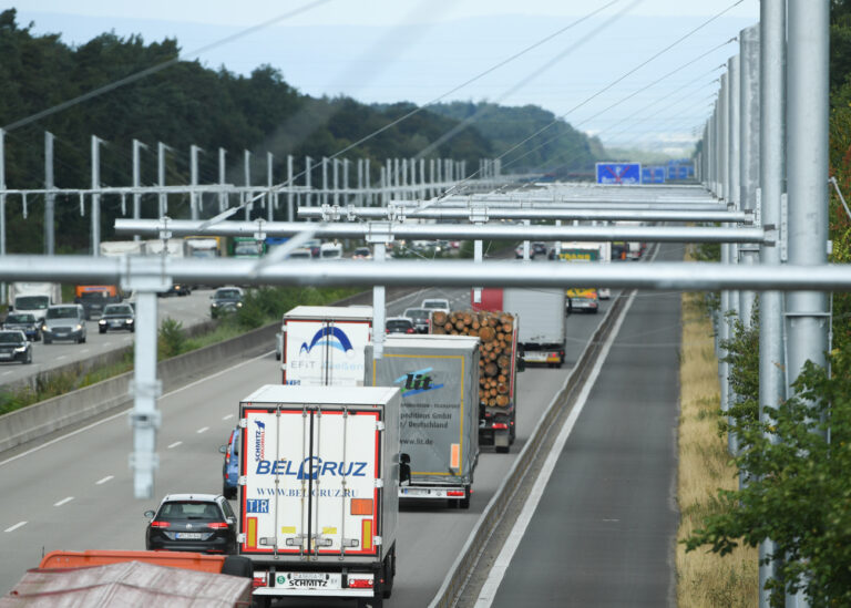 ARCHIV - 11.07.2018, Hessen, Gräfenhausen: Der Verkehr rollt an neuartigen Oberleitungsmasten vorbei, die an der Autobahn A5 nahe der Rastanlage Gräfenhausen stehen. Auf dem sogenannten eHighway sollen bald die ersten Spezial-Lastwagen mit Strom aus den Oberleitungen testweise fahren. (Zu dpa 