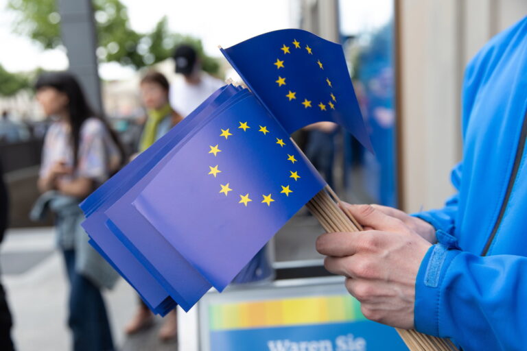 epa07602891 A man hands EU flags to people out side the offices of the European Commision in Berlin, Germany, 26 May 2019. The European Parliament election is held by member countries of the European Union (EU) from 23 to 26 May 2019. EPA/OMER MESSINGER