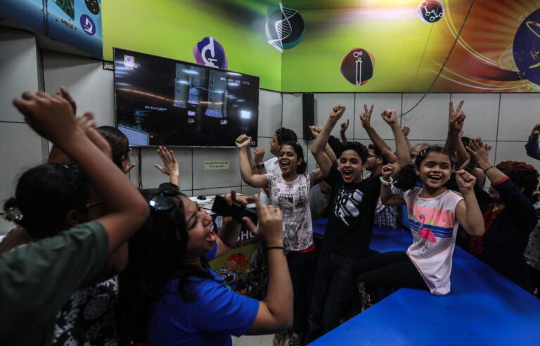 epa07733038 Indian people cheers and celebrates as they watch the live telecast of the Indian Space Research Organisation (ISRO) orbiter vehicle 'Chandrayaan-2', India's first moon lander and rover mission planned and developed by the ISRO GSLV MKIII-M1, at the Nehru Science Center, in Mumbai, India, 22 July 2019. EPA/DIVYAKANT SOLANKI