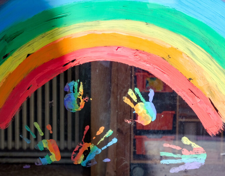 ARCHIV - 17.04.2020, Berlin: Kinderhände und ein Regenbogen sind an einer Kita zu sehen. Kinder von Alleinerziehenden und weiteren systemrelevanten Berufsgruppen dürfen ab heute wieder in die Kita. (zu 