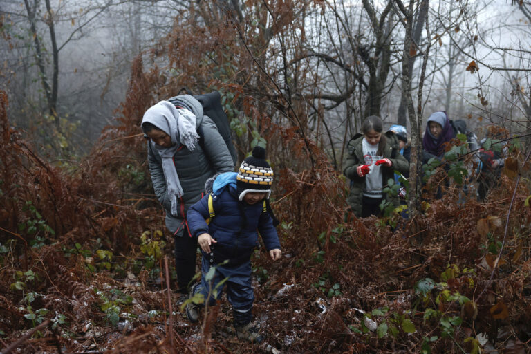 Alia and her 5-year old son walk through a Croatian forest with others after crossing the Bosnia-Croatia border near the Bosnian town of Velika Kladusa, Thursday Dec. 10, 2020. Entire migrant families are on the move in cold weather in Bosnia while trying to reach the West as the European Union warns the Balkan country it must act to prevent a humanitarian disaster. A statement by the EU Bosnia mission says current weather conditions are putting at risk the lives of more than 3,000 people sleeping rough or staying in inadequate conditions. (AP Photo/Marc Sanye)