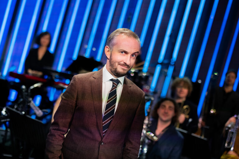 02.12.2021, Nordrhein-Westfalen, Köln: Jan Böhmermann, Moderator, steht im Anschluss an seine Late-Night-Show «ZDF Magazin Royal» vor seinem Orchester, dem Rundfunk Tanzorchester Ehrenfeld. Jan Böhmermann bezeichnet sich selbst als Theater-Kind - nun soll ihn die ganze Republik auf der Bühne sehen können. Der Satiriker verlässt sein Fernsehstudio und geht auf Musik-Tour. (zu dpa-Interview «Böhmermann geht auf Tour: «Uns fällt die Studiodecke auf den Kopf») Foto: Rolf Vennenbernd/dpa +++ dpa-Bildfunk +++ (KEYSTONE/DPA/Rolf Vennenbernd)