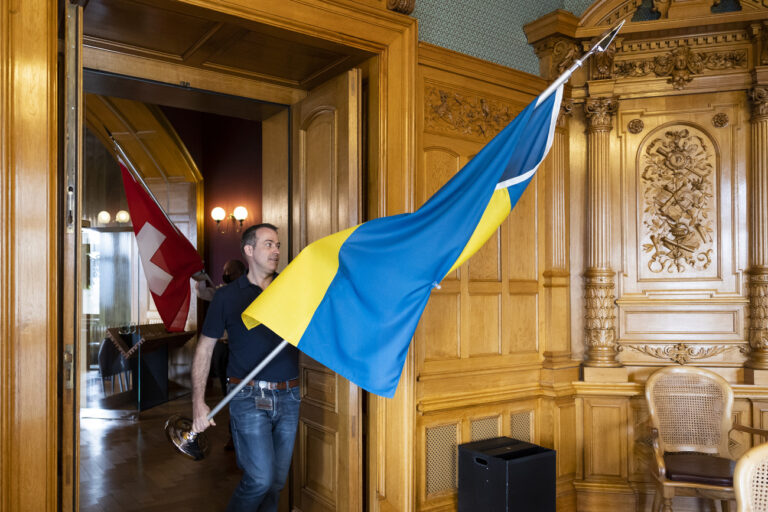 Angestellte der Parlamentsdienste installieren die Flaggen der Ukraine und der Schweiz in einem Sitzungszimmer im Bundeshaus, vor einer kurzfristig anberaumten Sitzung, am Mittwoch, 16. Maerz 2022, in Bern. Hans-Peter Portmann, Nationalrat FDP-ZH, traf sich mit ukrainischen Vertretern der Stiftung RIDNI, Berner Regierungspraesidentin Beatrice Simon und dem Gemeindepraesident von Kandersteg, Rene Maeder, um die Aufnahme von 160 Waisenkindern aus der Ukraine zu besprechen. (KEYSTONE/Peter Klaunzer)