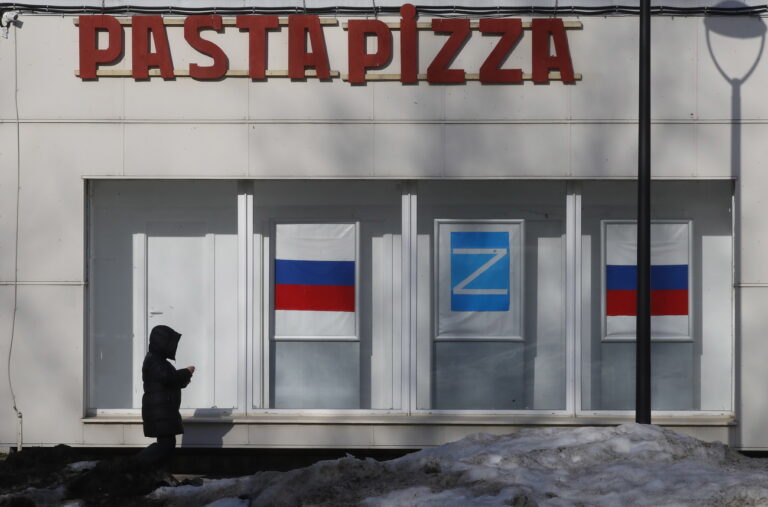 epa09842204 A woman walks past posters depicting the Russian flag and the letter Z in Kronstadt, outside St. Petersburg, Russia, 22 March 2022. The letter Z has been used by Russian forces as an identifying sign on their vehicles in Ukraine. On 24 February Russian troops had entered Ukrainian territory in what the Russian president declared a 'special military operation', resulting in fighting and destruction in the country, a huge flow of refugees, and multiple sanctions against Russia. EPA/ANATOLY MALTSEV