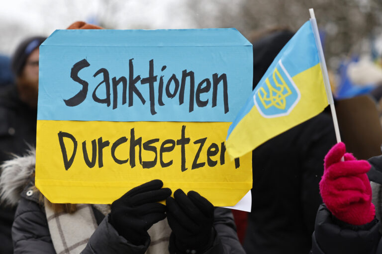 Protesters hold banners and Ukrainian flags during a national demonstration against the Russian invasion of Ukraine in Bern, Switzerland, Saturday, April 2, 2022. (KEYSTONE/Peter Klaunzer)