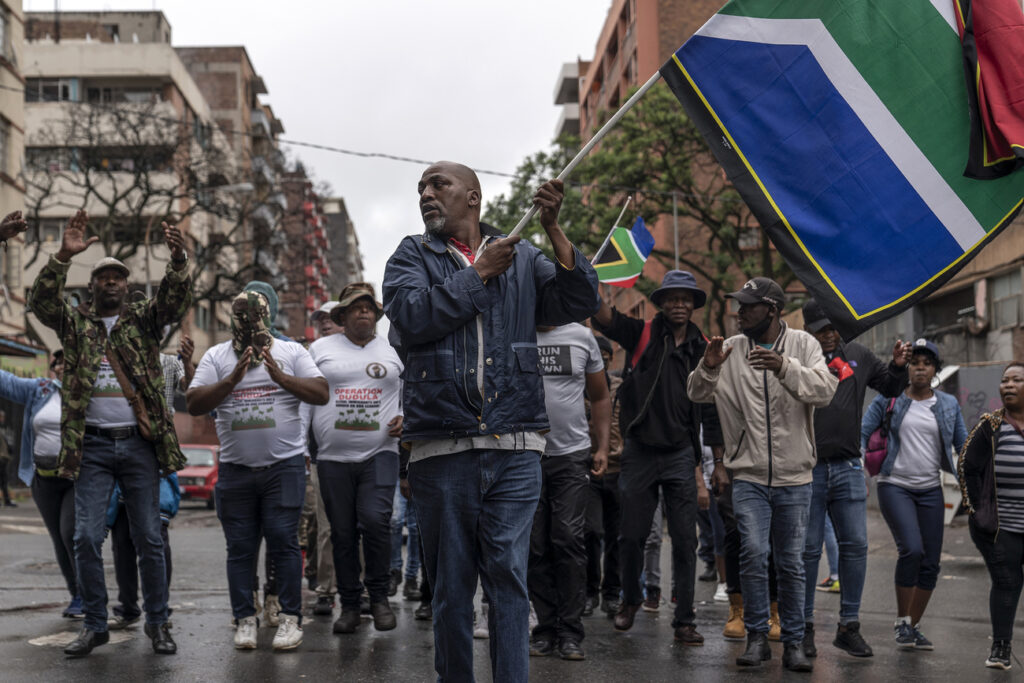 19 February 2022, South Africa, Johannesburg: A man holds up a South African flag as members of 