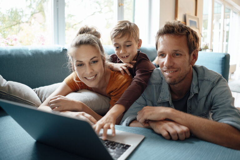 Happy family sharing laptop on sofa at home (KEYSTONE/WESTEND61/JOSEFFSON)
