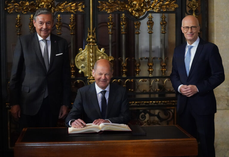 06 May 2022, Hamburg: German Chancellor Olaf Scholz (M, SPD), signs the guest book of the Überseeclub in the presence of Peter Tschentscher (r, SPD), First Mayor and President of the Senate of the Free and Hanseatic City of Hamburg, and Michael Behrendt, President of the Überseeclub, in front of the festive event 