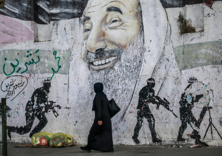 epa10014876 A Palestinian woman walks next to the graffiti of Hamas late leader Sheikh Ahmed Yassin, in Gaza City, 15 June 2022. This day on 15 June, marks the 15th anniversary of Hamas taking control of Gaza. EPA/MOHAMMED SABER