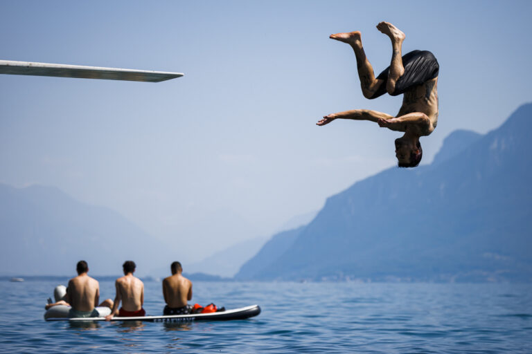 A man jumps into lake Geneva as a heat wave reaches the country, in Saint-Saphorin, Switzerland, Saturday, June 18, 2022. (KEYSTONE/Valentin Flauraud)