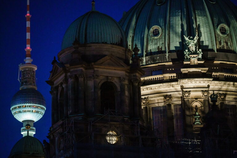 epa10094659 The Berlin Cathedral 'Berliner Dom' (R) shows only few signs of illumination in front of the TV tower in Berlin, Germany, 27 July 2022. Considering the war of Russia against Ukraine and Russia's energy policy, the Berlin Senate announced to turn off the illumination of public buildings, landmarks and statues in order to save energy costs. EPA/CLEMENS BILAN