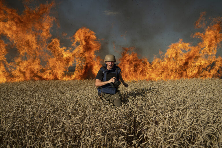 Photojournalist Evgeniy Maloletka runs from the fire in a burning wheat field during his assignment after Russian shelling, a few kilometres from Ukrainian-Russian border in the Kharkiv region, Ukraine, Friday, July 29, 2022. (AP Photo/Mstyslav Chernov)