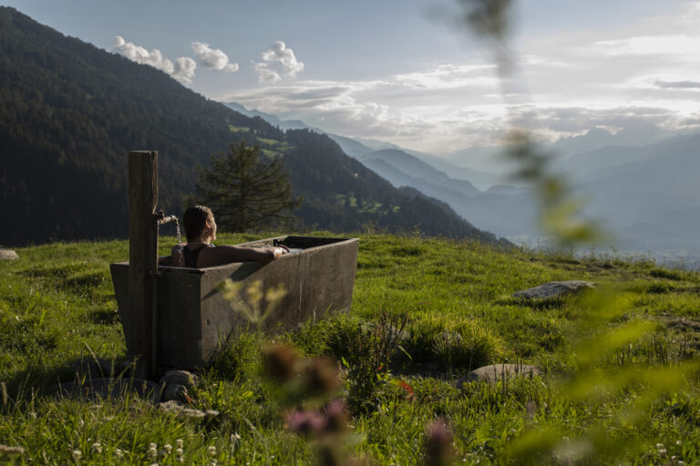 Eine Frau sitzt waehrend einer Hitzewelle in einem Brunnen auf der Alp Juchs, aufgenommen am Mittwoch, 3. August 2022, in Chur. (KEYSTONE/Gian Ehrenzeller)