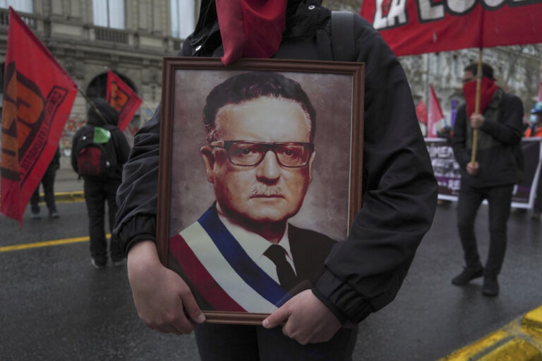 A demonstrator carries a portrait of late former President Salvador Allende during a march to commemorate the anniversary of the coup that toppled President Allende and brought dictator General Augusto Pinochet to power 49 years ago, in Santiago, Chile, Sunday, Sept. 11, 2022. The anniversary comes one week after Chileans overwhelmingly rejected a new constitution to replace its dictatorship-era charter. (AP Photo/Matias Basualdo)