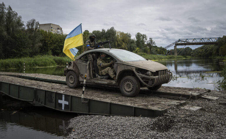 Ukrainian paratroopers drive on the vehicle with Ukrainian flag on the pantone bridge across Siverskiy-Donets river in the recently retaken area of Izium, Ukraine, Wednesday, Sept. 14, 2022. (AP Photo/Evgeniy Maloletka)