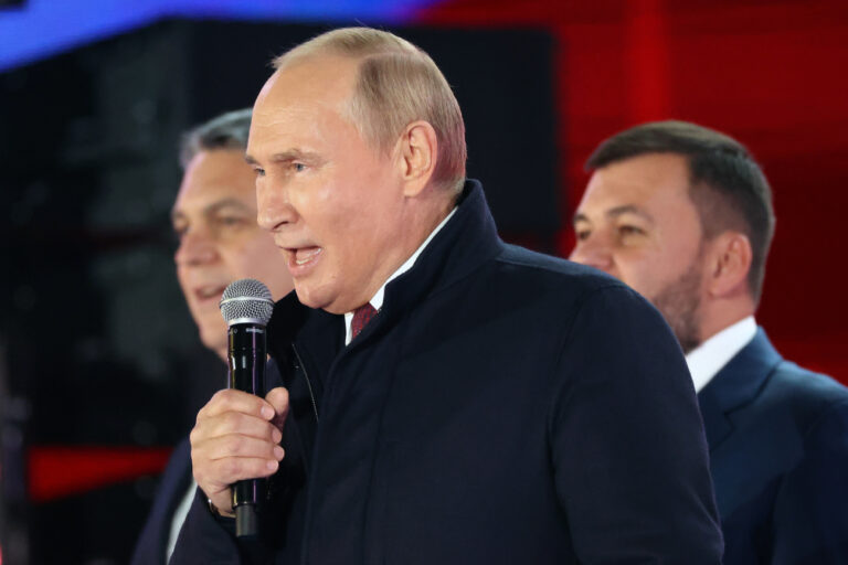 Russian President Vladimir Putin speaks as Leonid Pasechnik, leader of self-proclaimed Luhansk People's Republic, left, and Denis Pushilin, leader of self-proclaimed of the Donetsk People's Republic, right, stand near him during celebrations marking the incorporation of regions of Ukraine to join Russia in Red Square with the Spasskaya Tower on the right, in Moscow, Russia, Friday, Sept. 30, 2022. The signing of the treaties making the four regions part of Russia follows the completion of the Kremlin-orchestrated 