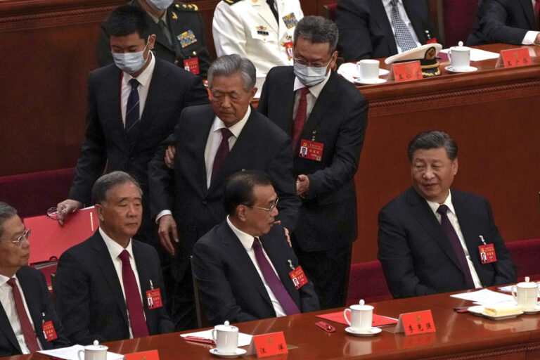 Chinese President Xi Jinping, right, looks on as former Chinese President Hu Jintao, standing at center, touches the shoulder of Premier Li Keqiang, center, as he is assisted to leave the hall during the closing ceremony of the 20th National Congress of China's ruling Communist Party at the Great Hall of the People in Beijing, Saturday, Oct. 22, 2022. (AP Photo/Andy Wong)