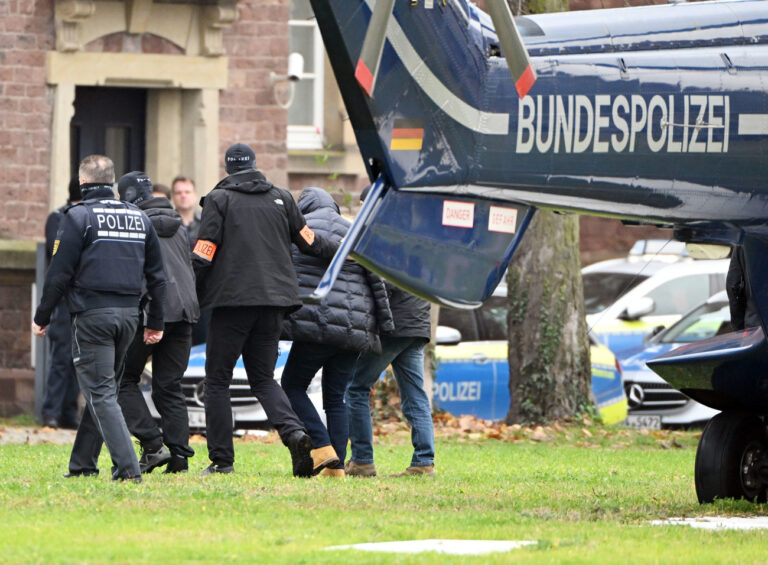07.12.2022, Baden-Württemberg, Karlsruhe: Eine Person (2.v.r.) wird von Polizisten aus einem Hubschrauber gebracht. Die Bundesanwaltschaft hat am Mittwochmorgen mehrere Menschen aus der sogenannten 