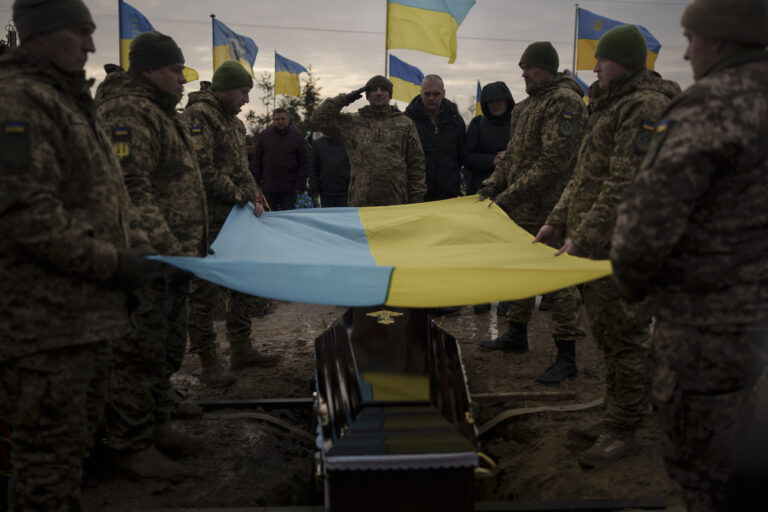 Ukrainian soldiers hold their national flag over the coffin of comrade Dmytro Kyrychenko, during his funeral in Bucha, outskirts of Kyiv, Ukraine, Friday, Dec. 23, 2022. The 33-year-old soldier died during a combat mission in the Donetsk region. (AP Photo/Felipe Dana)