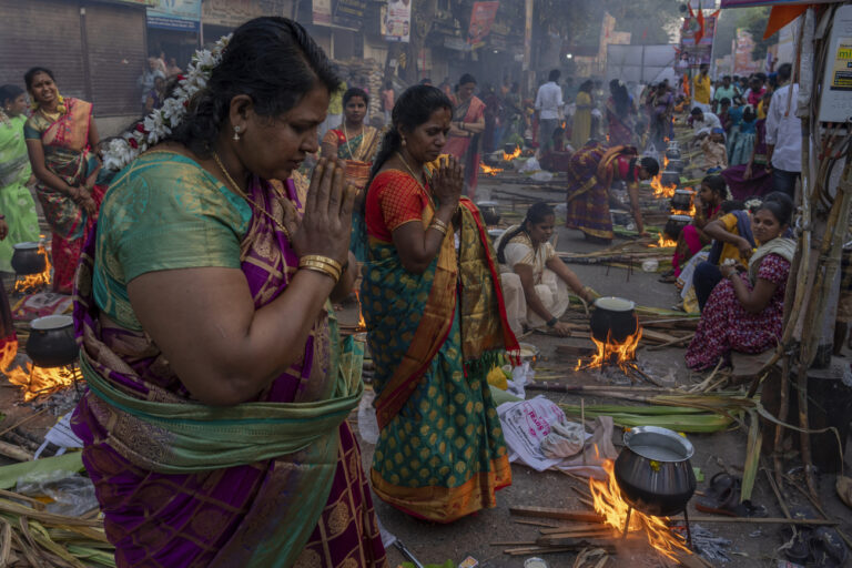 Indian Tamil Hindu woman offer prayers as they cooks special food to celebrate the harvest festival of Pongal at Dharavi, one of the world's largest slums, in Mumbai, India, Sunday, Jan. 15, 2023. This celebration, held according to the solar calendar, which marks the beginning of the sun's northward movement and considered to be auspicious. (AP Photo/Rafiq Maqbool)