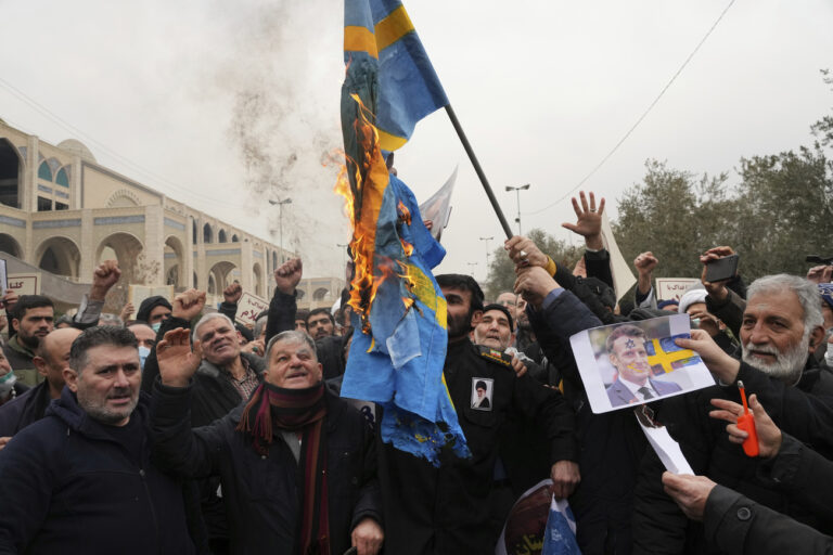 Protesters burn representations of the Swedish flag during a protest to denounce the recent desecration of Islam's holy book, Quran, by a far-right activist in Sweden, after Friday Prayers in Tehran, Iran, Friday, Jan. 27, 2023. (KEYSTONE/AP Photo/Vahid Salemi)
