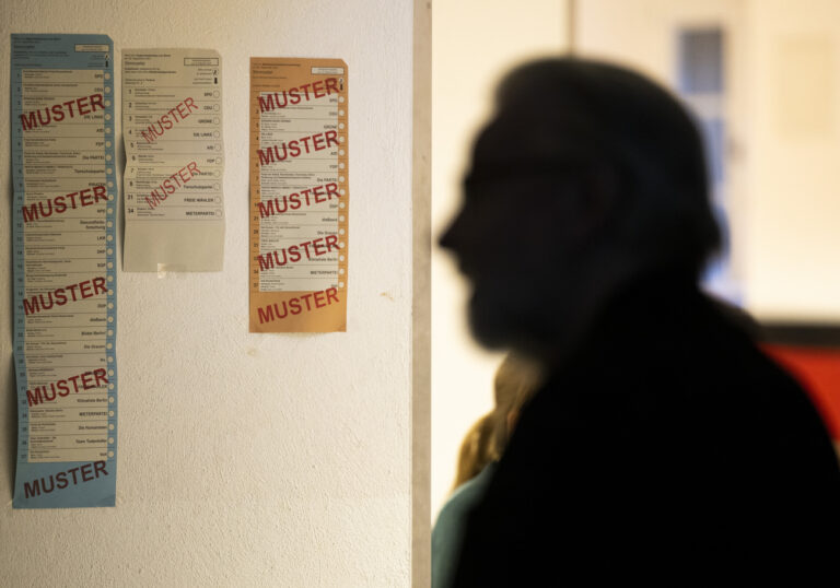 12.02.2023, Berlin: Ein Wähler steht am Morgen in einem Wahllokal im Berliner Bezirk Pankow, während an der Wand die Muster-Stimmzettel aufgehängt sind. Die im Nachhinein vom Berliner Verfassungsgerichtshof für ungültig erklärte Wahl zum 19. Abgeordnetenhaus von Berlin vom 26. September 2021 wird am Sonntag wiederholt. Foto: Monika Skolimowska/dpa +++ dpa-Bildfunk +++ (KEYSTONE/DPA/Monika Skolimowska)