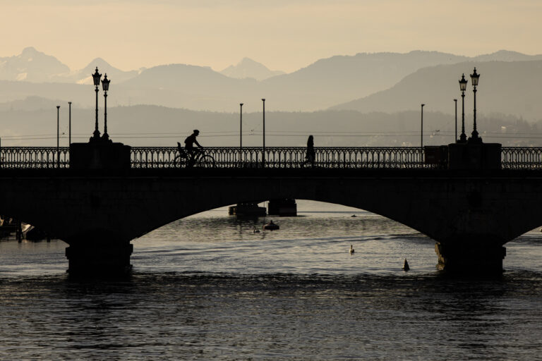 A cyclist rides next to a pedestrian over the Muensterbridge in Zurich, Switzerland on February 21, 2023. (KEYSTONE/Michael Buholzer).