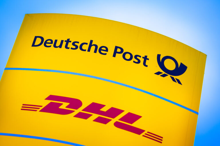 09.03.2023, Niedersachsen, Hannover: Die Logos von Deutsche Post und DHL leuchten am Morgen auf einem Schild vor einer Zustellbasis. Vor dem Hintergrund eines drohenden Streiks von Briefträgern und Paketboten legt die Deutsche Post am 09.03.2023 ihre Jahreszahlen vor. Erwartet wird ein Rekordergebnis. (zu dpa 