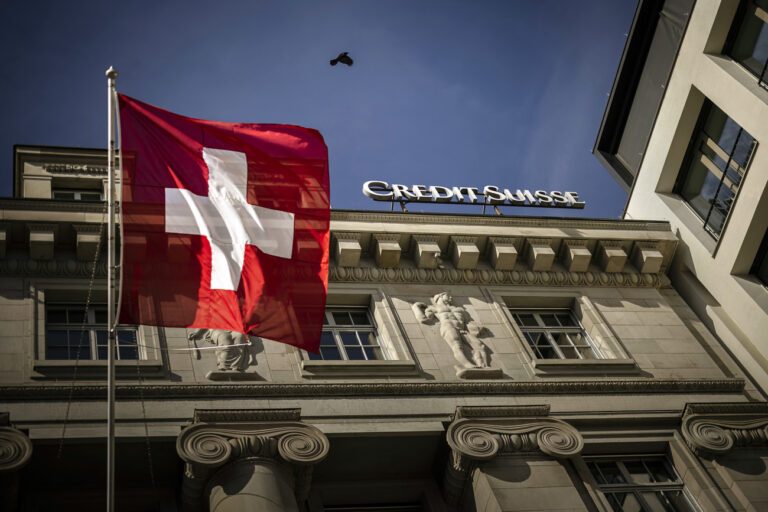 The logo of Swiss bank Credit Suisse is seen beside a Swiss flag on a building in Lucerne, Switzerland, on March 16, 2023. Credit Suisse, which was beset by problems long before the U.S. bank failures, said Thursday that it would exercise an option to borrow up to 50 billion francs ($53.7 billion) from the Swiss National Bank. (KEYSTONE/Michael Buholzer)