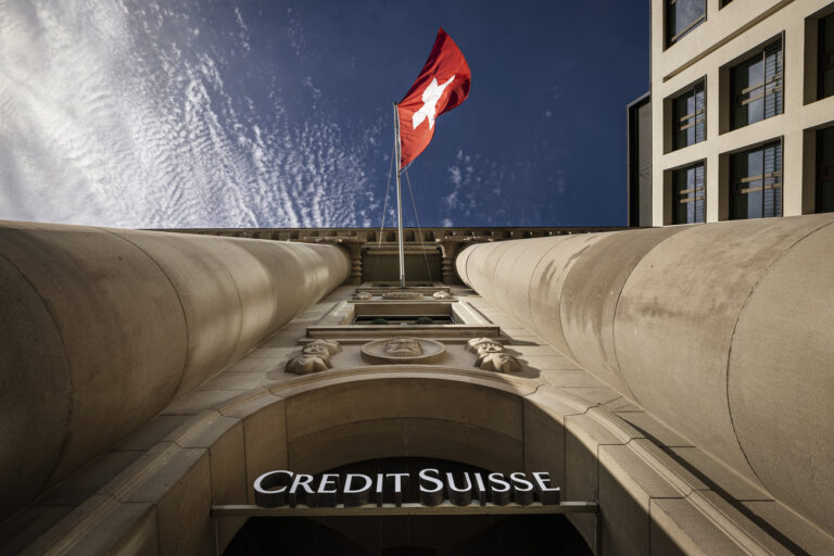 The logo of Swiss bank Credit Suisse is seen beside a Swiss flag on a building in Lucerne, Switzerland, on March 16, 2023. Credit Suisse, which was beset by problems long before the U.S. bank failures, said Thursday that it would exercise an option to borrow up to 50 billion francs ($53.7 billion) from the Swiss National Bank. (KEYSTONE/Michael Buholzer)