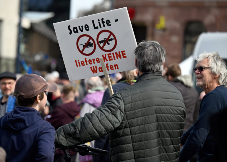 10.04.2023, Nordrhein-Westfalen, Dortmund: Teilnehmer des Ostermarsches Rhein/Ruhr stehen mit einem Protestplakat mit der Aufschrift 