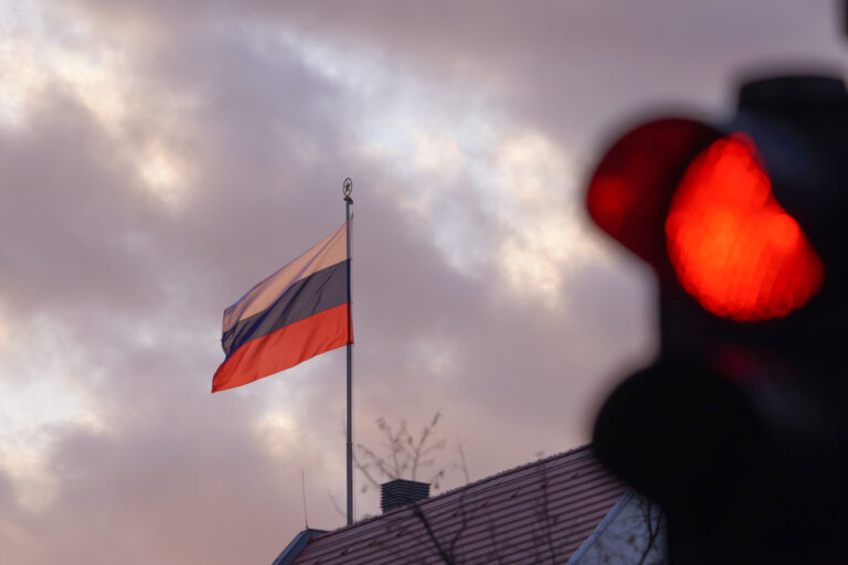ARCHIV - 24.02.2022, Berlin: Die Flagge der Russischen Botschaft weht am frühen Morgen vor einer roten Ampel. (Zu dpa 