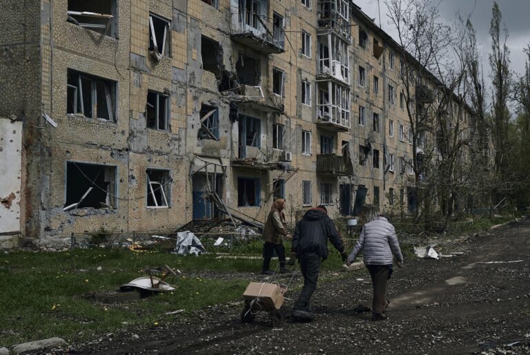 Local residents carry their belongings as they leave their home in Avdiivka, the site of heavy battles with the Russians, in the Donetsk region, Ukraine, Friday, April 28, 2023. (AP Photo/Libkos)