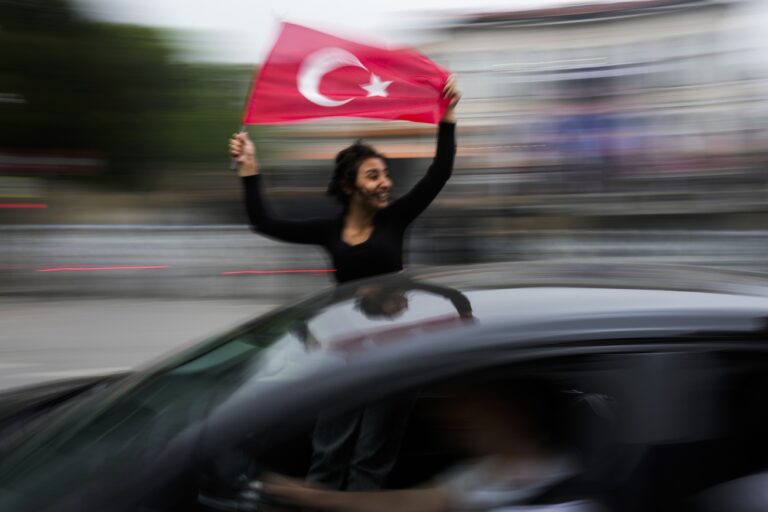A supporter of the President Recep Tayyip Erdogan holds a Turkish flag outside his house in Istanbul, Turkey, Sunday, May 28, 2023. President Recep Tayyip Erdogan, who has been at Turkey's helm for 20 years, is favored to win a new five-year term in the second-round runoff, after coming just short of outright victory in the first round on May 14.(AP Photo/Francisco Seco)