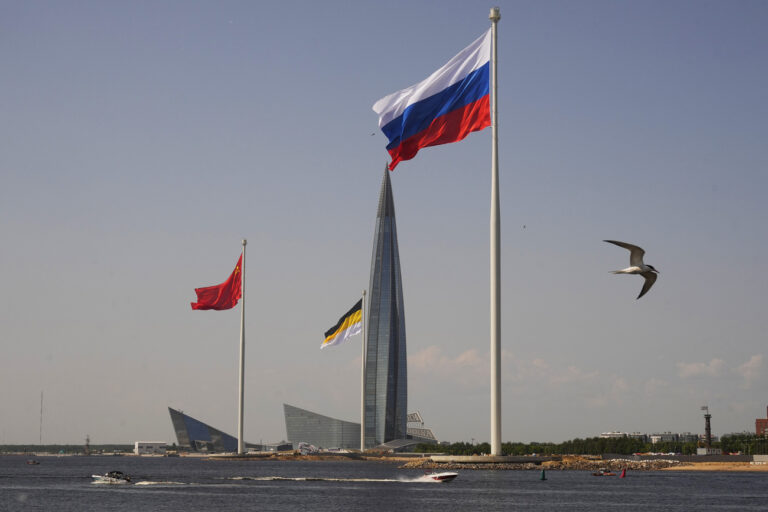 The Russian national, right, the former Soviet Union, left, and the former Russian Empire flags flutter in the wind during a ceremony of flags rising held by Gazprom on the coastline near the park of the 300th anniversary of St. Petersburg at the Gulf of Finland in St. Petersburg, Russia, Saturday, June 17, 2023, with the Lakhta Center skyscraper, the headquarters of Russian gas monopoly Gazprom in background. (AP Photo/Dmitri Lovetsky)