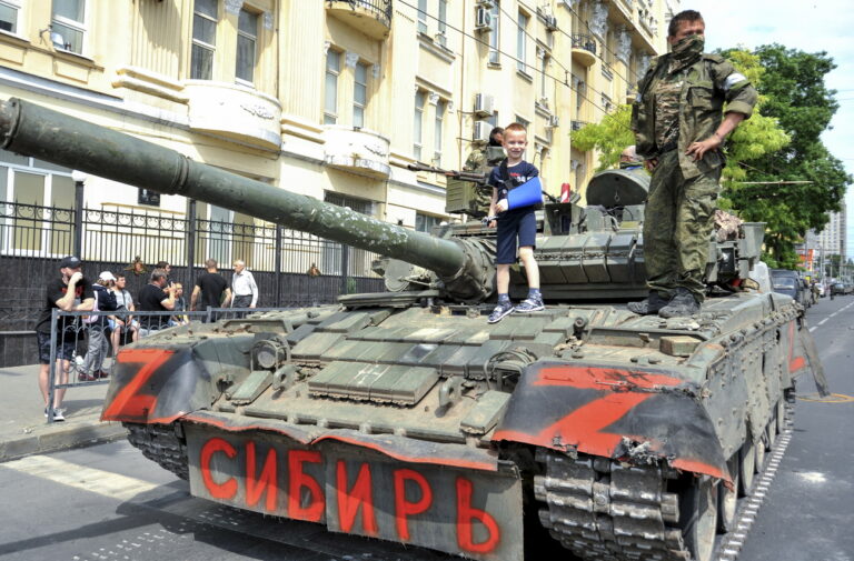 epa10709141 A child poses for a photo on a tank reading 'Siberia' as servicemen from private military company (PMC) Wagner Group block a street in downtown Rostov-on-Don, southern Russia, 24 June 2023. Security and armoured vehicles were deployed after Wagner Group's chief Yevgeny Prigozhin said in a video that his troops had occupied the building of the headquarters of the Southern Military District, demanding a meeting with RussiaâÄ™s defense chiefs. EPA/ARKADY BUDNITSKY